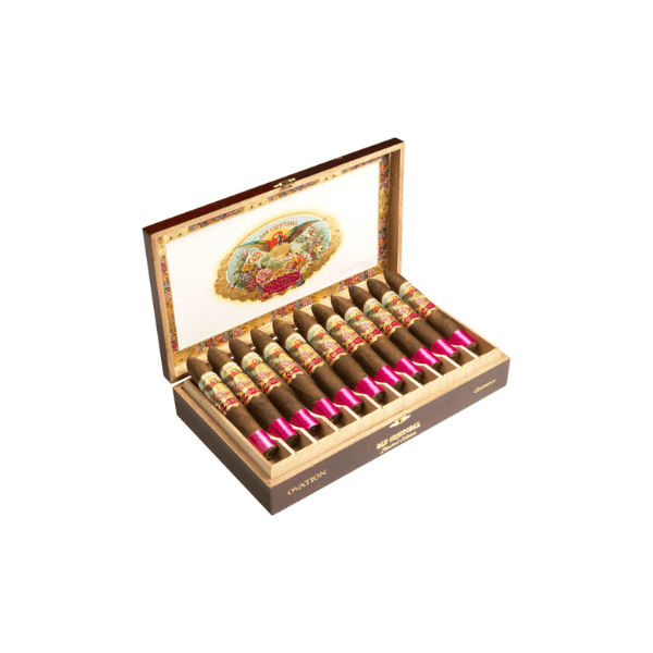 An open wooden box of San Cristobal Ovation Eminence by San Cristobal displays twelve luxury cigars, each with Nicaraguan fillers, pink foil accents, decorative bands, and a colorful ornate illustration inside the lid.