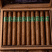 A wooden box containing ten brown cigars with green and gold labels, arranged in a single row, featuring the Big Sky Cigar Madison Toro from the Montana River Series—a premium cigar with a Habano wrapper.