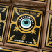 Box of Crowned Heads Thunderkiss Robusto cigars featuring an eye motif and gold accents, highlighted by text noting 10 boutique cigars in each 5x54 box. These premium smokes showcase an Ecuadorian Habano Maduro wrapper, blending bold visuals with outstanding craftsmanship.