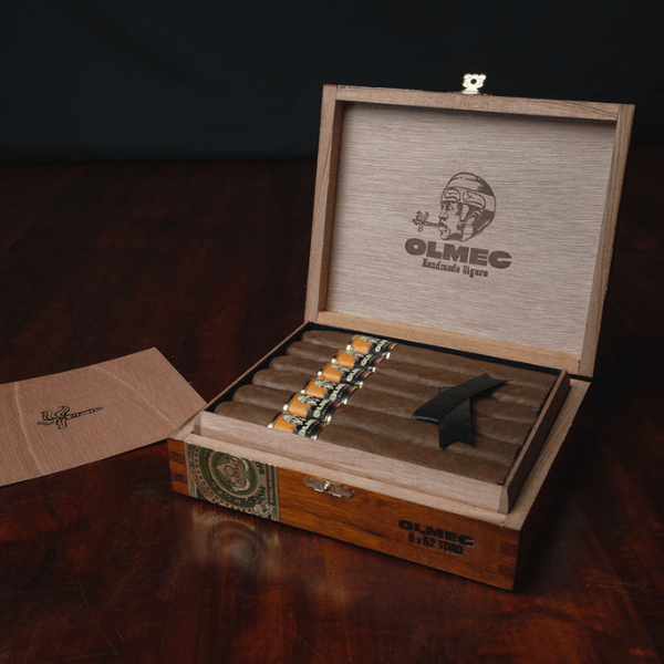 Open wooden box containing six Foundation Olmec Claro Robusto cigars, with a brand logo and text printed on the inside of the lid.