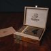 Open wooden box containing six Foundation Olmec Claro Robusto cigars, with a brand logo and text printed on the inside of the lid.