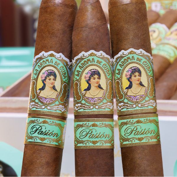 Three La Aroma De Cuba Pasion Robusto cigars stand in a box, each with vintage-style bands showing a woman's portrait—a classic Nicaraguan puro from La Aroma De Cuba.
